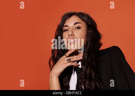 Une jeune femme dans une veste noire et une cravate repose soigneusement son menton sur sa main. Elle regarde vers le haut. Banque D'Images