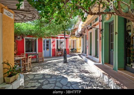 Ruelle colorée à Preveza, en Grèce, avec des tavernes traditionnelles, chemin pavé ombragé et charme méditerranéen dans un cadre paisible et ensoleillé. Banque D'Images