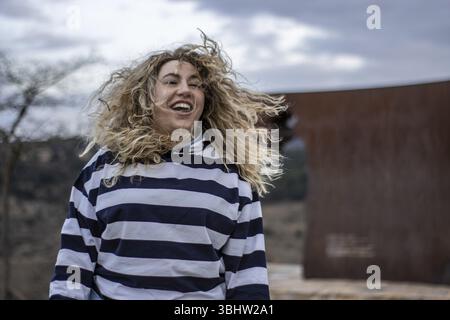 Portrait de femme blonde aux cheveux bouclés souriante et jouissant dans la rue Banque D'Images
