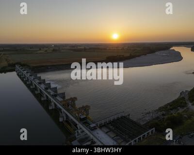 Capturé au coucher du soleil au printemps, ce drone montre le barrage d’Isola Serafini sur le fleuve Pô, où un nouveau passage de poissons reconnecte l’habit de l’esturgeon et de l’anguille Banque D'Images