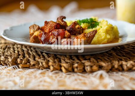 Morceaux de porc juteux cuits avec purée de pommes de terre sur l'assiette, smoothie aux fruits dans le verre, gros plan. Banque D'Images