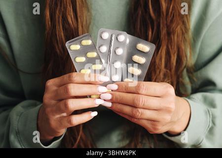 Mains tenant les plaquettes thermoformées. Femme montrant des vitamines ou des médicaments. Concept de soins de santé. Gros plan sur les suppléments. Emballage pharmaceutique. Banque D'Images
