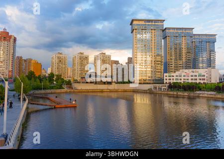 Kiev, Ukraine - 19 mai 2025 : vue grand angle mettant en valeur le front de mer pittoresque avec une architecture moderne et des reflets à Kiev pendant le coucher du soleil. Banque D'Images