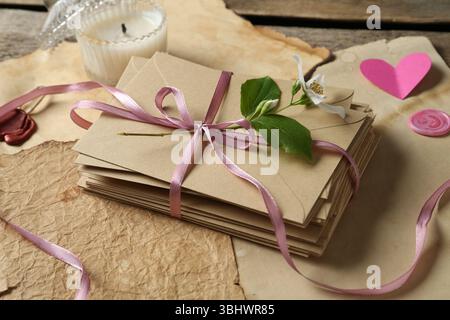 Pile de lettres d'amour, fleur, coeurs en papier, bougie et feuilles de parchemin sur la table en bois, gros plan Banque D'Images