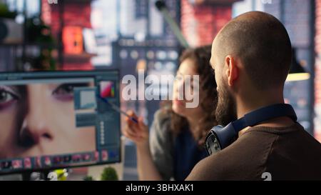 Graphiste et photographe collaborent dans un studio moderne, en utilisant des logiciels et des outils de retouche photo sur PC. L'équipe effectue des retouches avec des outils avancés de réglage de l'image. Caméra B. Banque D'Images