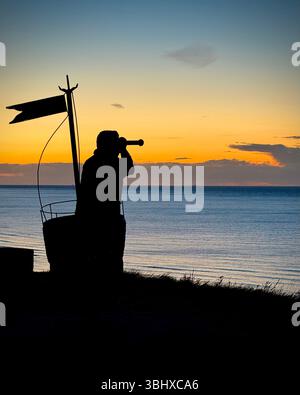 Statue de marin regardant le coucher du soleil sur la mer du Nord à Whitby, Yorkshire, Angleterre Banque D'Images