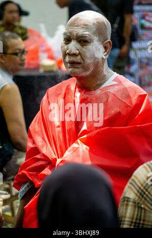 Le vieil homme chauve couvrit son corps d'un tissu rouge. Son visage était couvert de poudre blanche. Banque D'Images