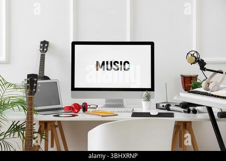 Lieu de travail avec ordinateur et instruments de musique près du mur de lumière dans le studio Banque D'Images