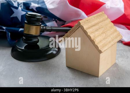 Drapeau américain avec Gavel et Toy Wooden House symbolisant les aspects juridiques de la propriété et des valeurs américaines Banque D'Images