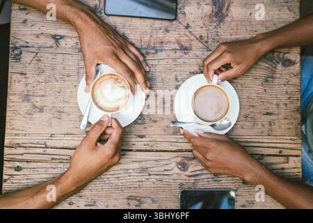 Couple tenant des tasses à café à la table en bois dans un cadre de café intérieur Banque D'Images