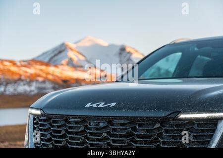 Karakol, Kirghizistan - 12 octobre 2024 : gros plan de la calandre avant et du logo moderne d'une nouvelle génération de Kia Sorento 4X, avec des montagnes floues Banque D'Images