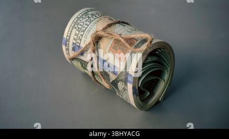 Paquet roulé de billets en dollars américains lié avec ficelle : symbolisme financier et importance économique Banque D'Images