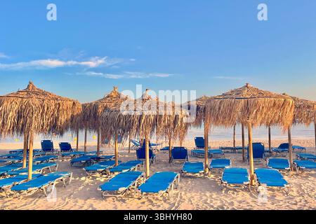 Chaises longues chaotiques et parasols à feuilles de palmier sur la plage d'Elafonissi, Crète, Grèce Banque D'Images