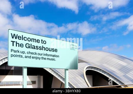 Panneau lisant 'Bienvenue à la Glasshouse' avec la structure architecturale moderne de la Sage en arrière-plan sous un ciel bleu newcastle upon tyne, Royaume-Uni Banque D'Images