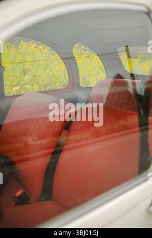 Une voiture Citroën Two Horses classique avec un intérieur rouge rétro capturé par une fenêtre. L'image souligne le design unique de cette voiture emblématique Banque D'Images