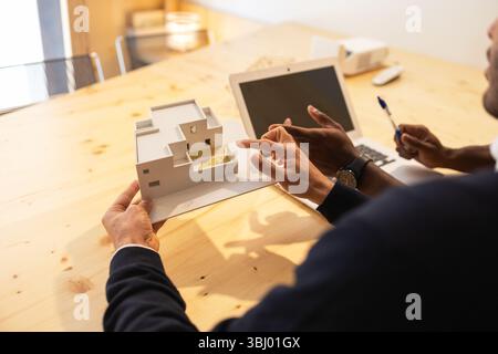 Deux collègues collaborent sur un projet dans un espace de coworking à Barcelone. Un ordinateur portable et un modèle architectural sont sur la table, indiquant un travail créatif Banque D'Images