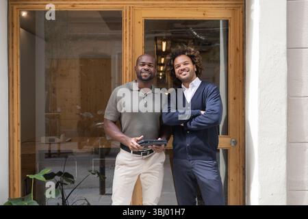 Deux professionnels se tiennent en toute confiance devant un élégant espace de coworking à Barcelone, illustrant la collaboration et les environnements de travail modernes dans une urba Banque D'Images