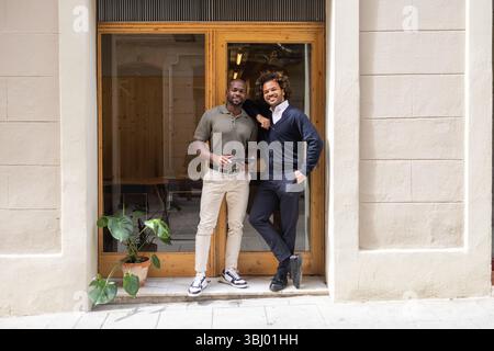 Deux professionnels souriants devant un espace de coworking à Barcelone, mettant en valeur un environnement de travail moderne et collaboratif. Parfait pour la mise en réseau a Banque D'Images