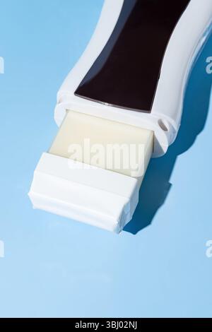 Une image en gros plan d'un rouleau sur une cartouche d'épilation sur un fond bleu, mettant en valeur son design pratique pour une épilation facile et en douceur. Idéal pour profess Banque D'Images