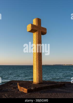 Photo verticale d'une croix de pierre sur le front de mer à Saint-Malo, France. Lumière chaude de coucher de soleil, horizon marin ouvert et ciel dégagé en Bretagne. Symbole fort Banque D'Images