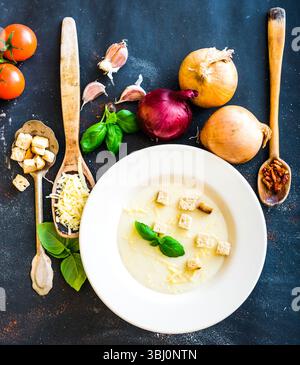 purée de soupe d'oignon dans une assiette blanche avec des légumes sur le fond noir Banque D'Images