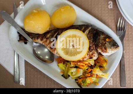 Une dourada grillée, des pommes de terre rôties et des légumes : un classique du restaurant portugais. Banque D'Images