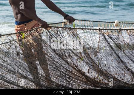 Demi-corps d'un pêcheur non identifié tirant un filet de pêche. fruits de mer, passe-temps. Brésil Banque D'Images