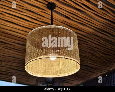 Lueur chaude d'une suspension en rotin sous un plafond en bambou Banque D'Images