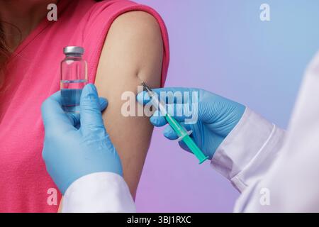Travailleur de la santé en gants administrant le vaccin avec une seringue au bras d'un patient, soulignant l'immunisation et la prévention des maladies. Banque D'Images