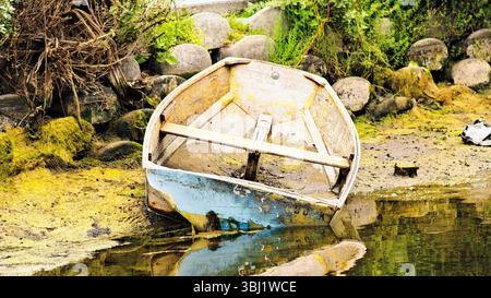Une barque altérée repose le long des canaux peu profonds de Venise à Los Angeles, sa peinture écaillée et ses reflets doux créant un moment rustique et calme à proximité Banque D'Images