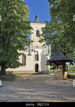 Vieux puits traditionnel en bois et pierre et le clocher entouré de vieux chênes dans la cour du monastère de Capriana, République de Moldavie Banque D'Images