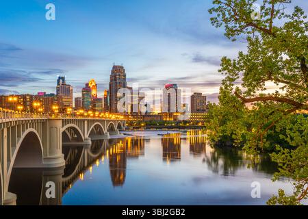 Minneapolis, Minnesota, USA ligne d'horizon du centre-ville sur le fleuve Mississippi avec le pont de la troisième Avenue au crépuscule. Banque D'Images