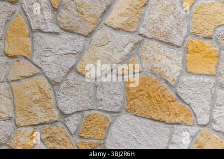 Un beau mur en pierre texturée avec des tons chauds qui améliorent son attrait esthétique Banque D'Images