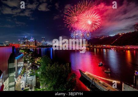 Des feux d'artifice roses et violets explosent au-dessus de la rivière Ohio au point State Park à Pittsburgh lors d'une célébration du 4 juillet avec vue sur la ville. Banque D'Images