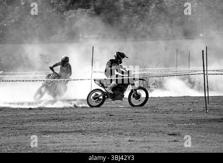 Les motards tout-terrain courent sur une piste poussiéreuse lors d'un rallye moto en Inde, mettant en valeur leurs compétences, leur vitesse et leur adernaline. Banque D'Images
