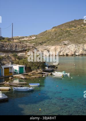 Huttes de pêche vibrantes et falaises rocheuses à Mandrakia, Milos, Grèce. L'eau turquoise et la lumière vive capturent le charme tranquille de ce village insulaire. Banque D'Images