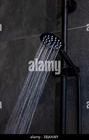 Il s'agit d'une vue rapprochée détaillée d'une pomme de douche avec de l'eau magnifiquement en cascade, illustrant sa fonction et son design Banque D'Images