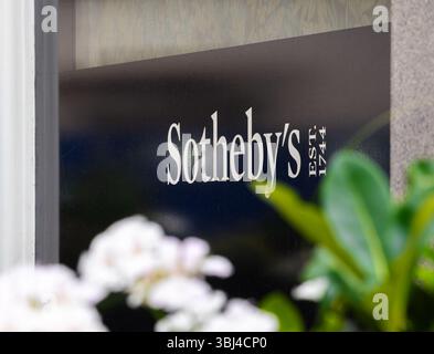 Londres, Royaume-Uni - 26 mai 2025 : vue rapprochée d'un panneau Sothebys, présentant le nom de la marque et l'année d'établissement, avec des fleurs floues dedans Banque D'Images