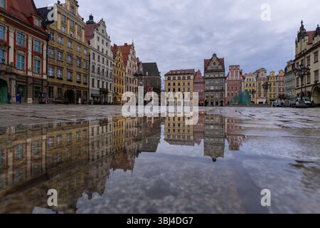 Wroclaw, Pologne - janvier 29 2025 : les célèbres bâtiments anciens se reflètent dans une flaque d'eau sur la place du marché médiéval de la vieille ville de Wroclaw en Pologne. Banque D'Images