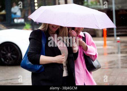Non exclusif : deux femmes souriantes marchent sous un parapluie rose alors qu’il pleut à Kiev, en Ukraine, le 12 juin 2025. (Photo de Kirill Chubotin/Ukrinform) Banque D'Images