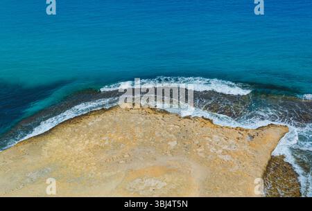 Vue de dessus de la côte avec sable jaune rencontrant l'eau bleue Banque D'Images
