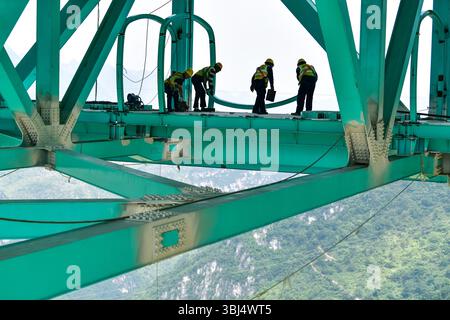 (250613) -- GUANLING, 13 juin 2025 (Xinhua) -- des ouvriers construisent un couloir touristique sur le chantier de construction du pont du Grand Canyon de Huajiang dans la province du Guizhou, au sud-ouest de la Chine, le 11 juin 2025. Du matériel lié au tourisme au pont du Grand Canyon de Huajiang est en construction. Le pont suspendu a une hauteur verticale de 625 mètres depuis le pont jusqu'à la surface de la rivière -- environ deux fois la hauteur de la Tour Eiffel. Le pont de 2 890 mètres, avec une portée de 1 420 mètres, est également le plus grand pont de portée du monde construit dans une zone montagneuse. Il devrait ouvrir à traffi Banque D'Images