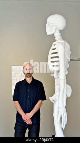 Édimbourg, Écosse, Royaume-Uni. 13 juin 2025. Le sculpteur écossais primé Kenny Hunter apporte ses œuvres contemporaines à la Fine Art Society cet été. Oublions, Hunter expérimente des utilisations inattendues de l'échelle, du matériel et du sujet. Kenny Hunter avec sa sculpture squelette. Commençant demain à la Fine Art Society de Dundas Street et se déroulant parallèlement au festival d'Édimbourg qui se termine le 30 août. Crédit : Craig Brown/Alamy Live News Banque D'Images