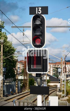 Feu rouge indiquant le numéro treize et indiquant un arrêt à un passage à niveau, assurant la sécurité des piétons et des véhicules Banque D'Images