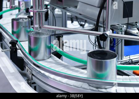 Produits alimentaires en conserve sur le tapis transporteur dans l'entrepôt de distribution. Concept du système de transport des colis Banque D'Images