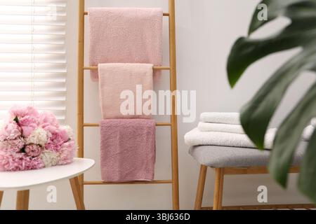 Serviettes douces sur l'échelle décorative en bois et fleurs de pivoine à l'intérieur Banque D'Images