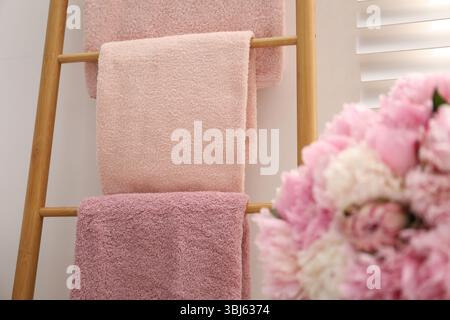Serviettes douces sur l'échelle décorative en bois et fleurs de pivoine à l'intérieur, gros plan Banque D'Images