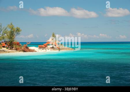 Petite île tropicale avec des équipements de construction sur sable blanc, entourée de turquoise et bleu profond océan sous un ciel clair Banque D'Images
