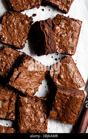 Une vue de dessus de brownies au chocolat avec un dessus croustillant sur papier parchemin. Banque D'Images