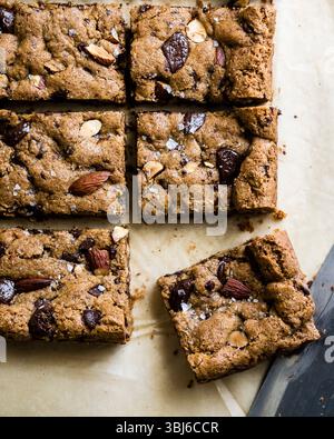 Carrés d'amandes fraîchement cuites et blondies aux pépites de chocolat sur papier parchemin. Banque D'Images